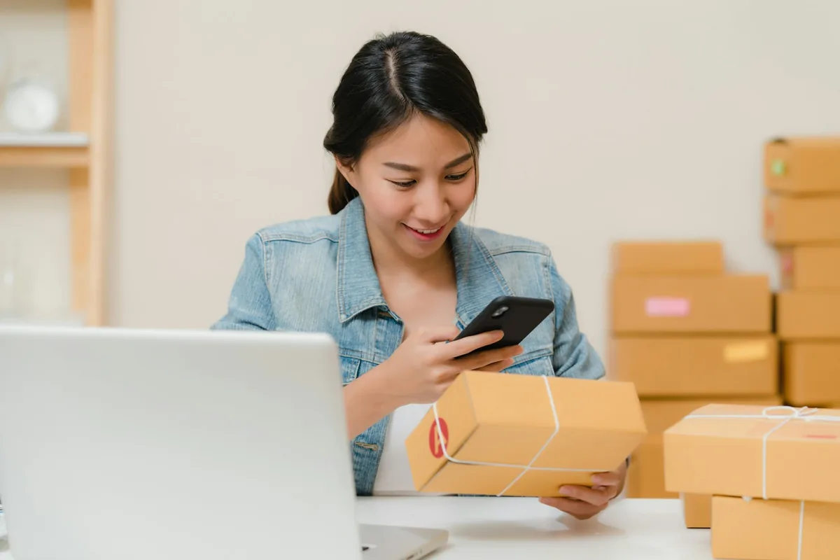 Shop owner checking a parcel beside a laptop